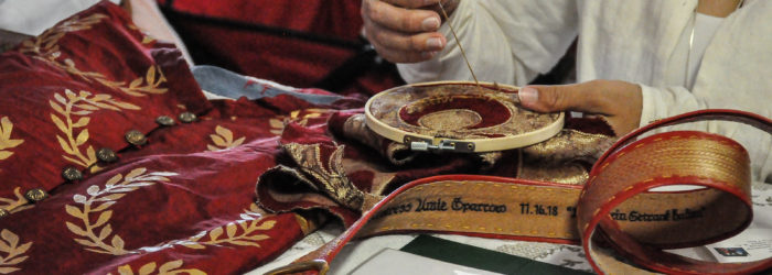 Embroiderer working on a crescent pattern on a garment